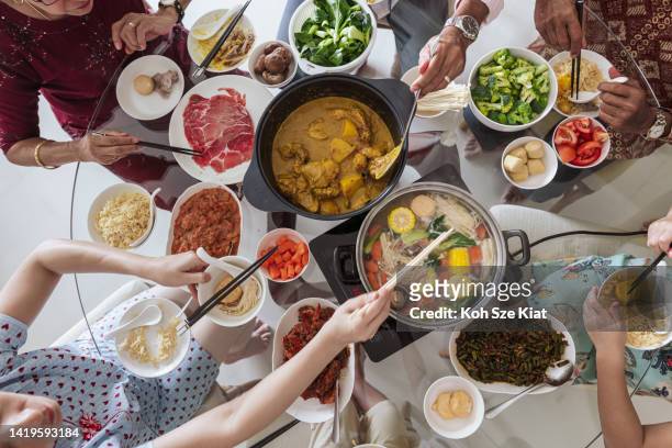 chinese new year - overhead shot of a multi racial family having a reunion meal - singapore food stockfoto's en -beelden