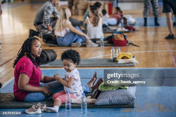 mother and child in shelter after natural disaster - homeless family stock pictures, royalty-free photos & images