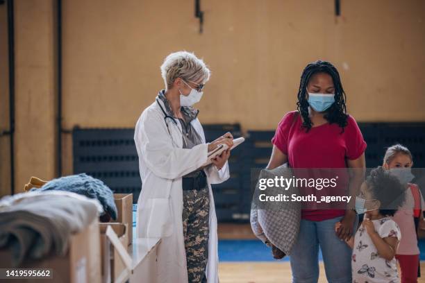 army doctor with civilians after natural disaster - migrant crisis in europe bildbanksfoton och bilder