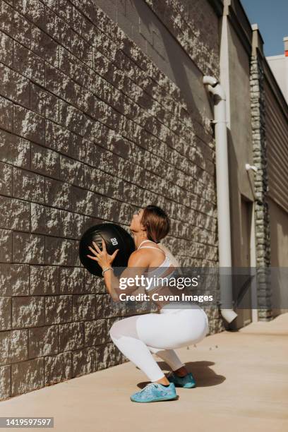 fit woman doing wall balls outside wearing white workout clothin - saint georges college stock pictures, royalty-free photos & images