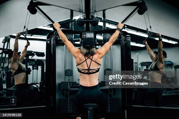 muscular woman using machine at gym wearing black workout clothi - saint georges college stock pictures, royalty-free photos & images