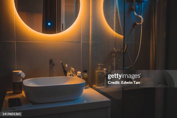 warm light cozy interior of bathroom with mirror reflection and sink basin - efeito de luz imagens e fotografias de stock