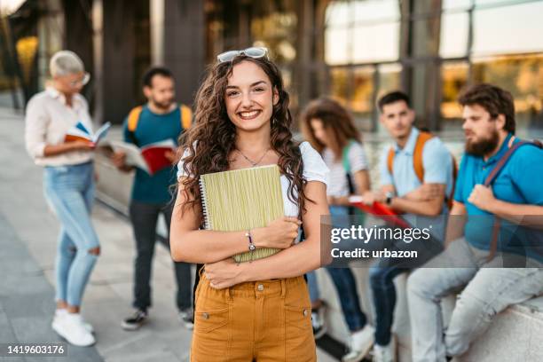 beautiful smiling female college student - college student holding books stockfoto's en -beelden