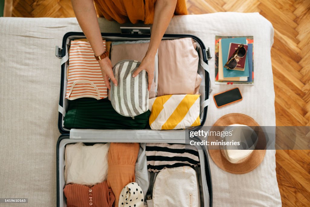 Cropped Photo of an Unrecognizable Woman Putting a Cosmetic Bag in Her Suitcase