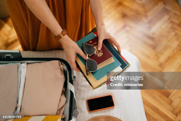 anonymous woman packing books and a passport for a vacation trip - passport open stock pictures, royalty-free photos & images