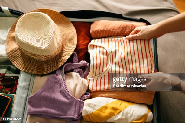 top view shot di una donna anonima che prepara una camicia in una valigia per le vacanze estive - imballare foto e immagini stock