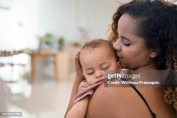 close up of mother cuddling sleeping baby daughter at home - can't leave baby stock pictures, royalty-free photos & images