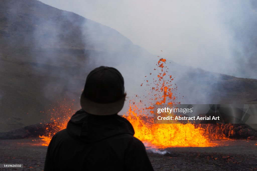 One tourist standing close to an erupting volcano, Iceland