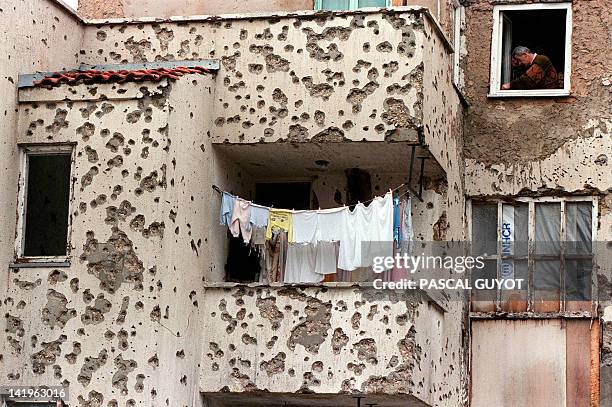 Resident tries to fix up a window of his flat in his bullet-riddled building in the eastern district of Mostar, southern Bosnia, on December 21 as a...