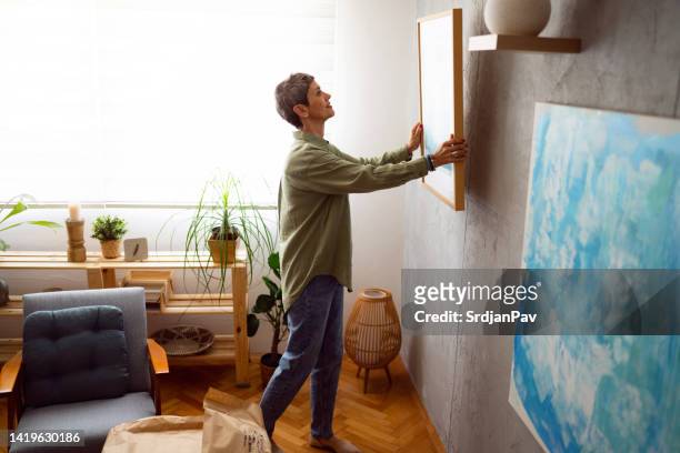 woman decorating her home with a new painting - art and craft stock pictures, royalty-free photos & images