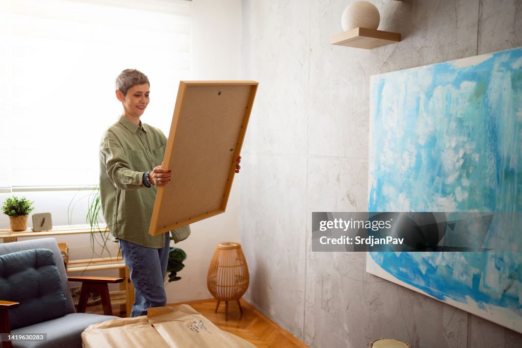 Frau bereitet ein neues Gemälde vor, um es an die Wand zu hängen