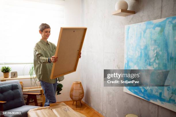 mujer preparando un nuevo cuadro para colgarlo en la pared - pintura-producto-artístico fotografías e imágenes de stock