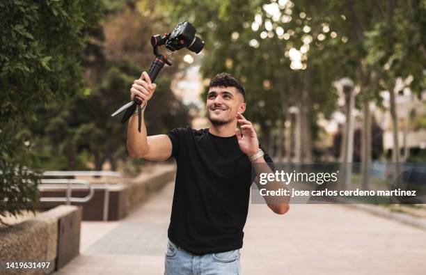 young adult vlogger shoots a video with a camera in the city, influencer - vinyl film stockfoto's en -beelden