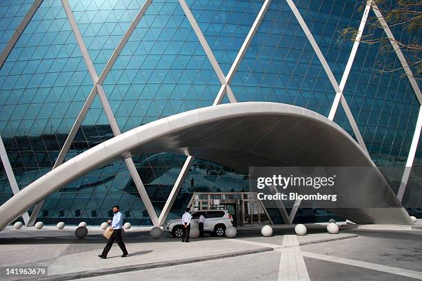 Employees wait by a vehicle at the entrance to the headquarters of Aldar Properties PJSC, Abu Dhabi's biggest real estate company, in Abu Dhabi,...