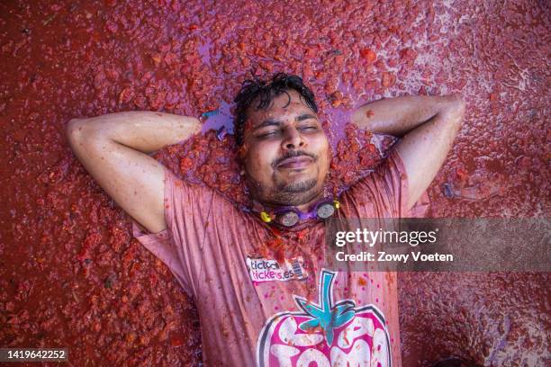 Reveler lays in tomato juice and pulp during the Tomatina festival on August 31, 2022 in Bunol, Spain. The world's largest food fight festival, La...