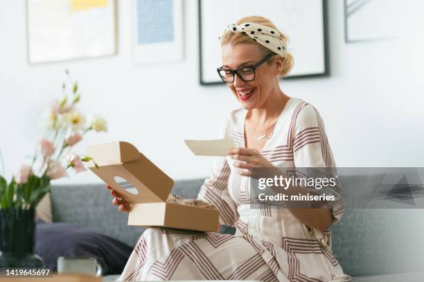 beautiful happy woman at home reading a note from a gift box - opening delivery stock pictures, royalty-free photos & images