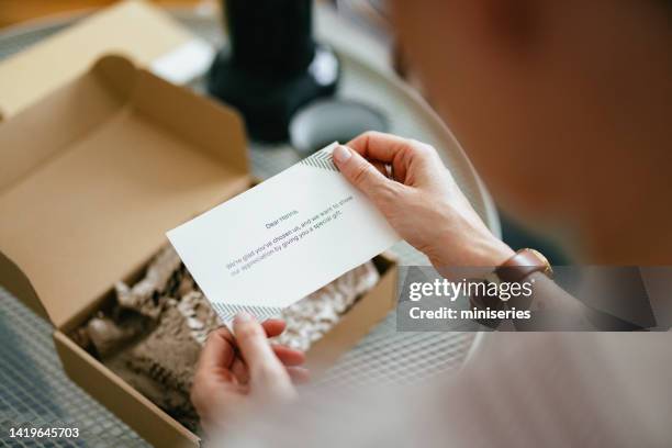 mujer anónima leyendo una nota de una caja de regalo (espacio de copia) - receiving fotografías e imágenes de stock