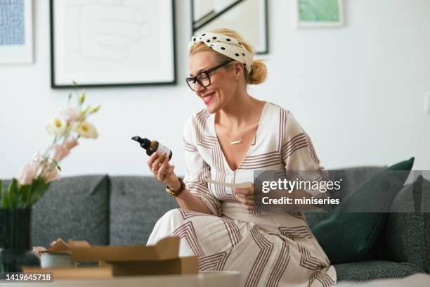 beautiful happy woman at home looking at products that arrived in a gift box - cosmetics box stock pictures, royalty-free photos & images