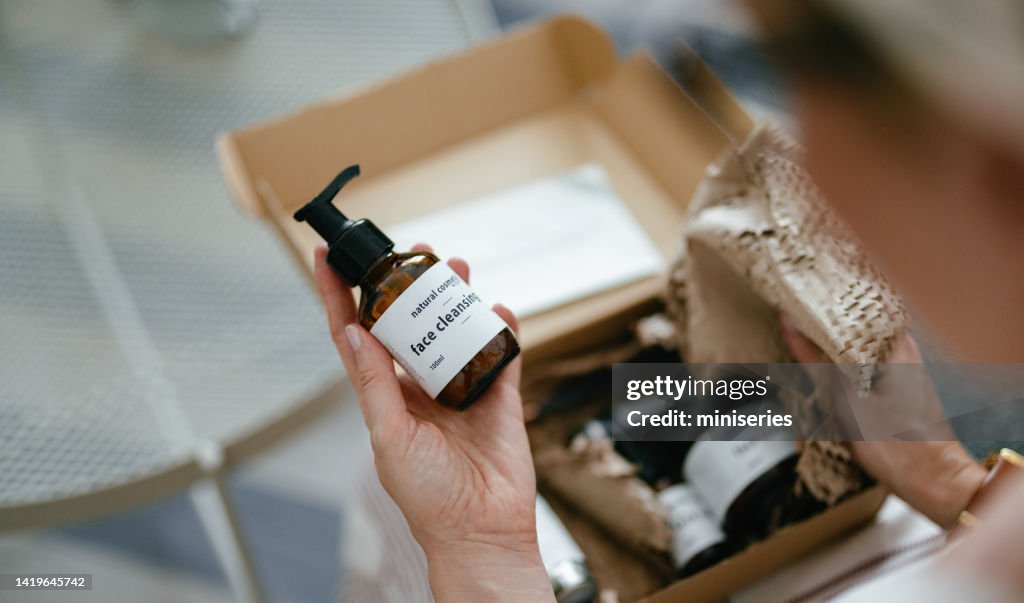 Anonymous Woman Holding a Gift Box and Looking at Beauty Cosmetics Products Inside (Copy Space)