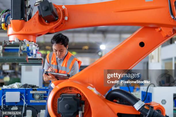 japanese engineer inspecting the robotic collaborative conveyor systems during installation in factory. - automation technology stock pictures, royalty-free photos & images