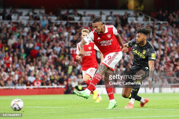 Gabriel Jesus of Arsenal scores their side's first goal whilst under pressure from Tyrone Mings of Aston Villa during the Premier League match...