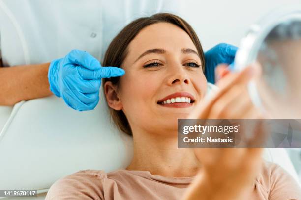 hermosa mujer en tratamiento facial mirando al espejo - indulgence fotografías e imágenes de stock