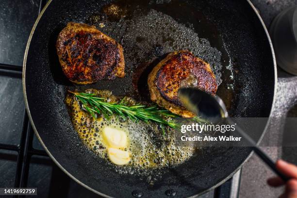 fillet steak in frying pan with butter and herbs - bañar en su jugo durante la cocción fotografías e imágenes de stock