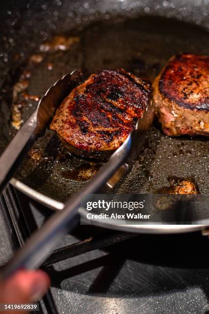 tongs holding fillet steak in frying pan - burnt pot stock pictures, royalty-free photos & images