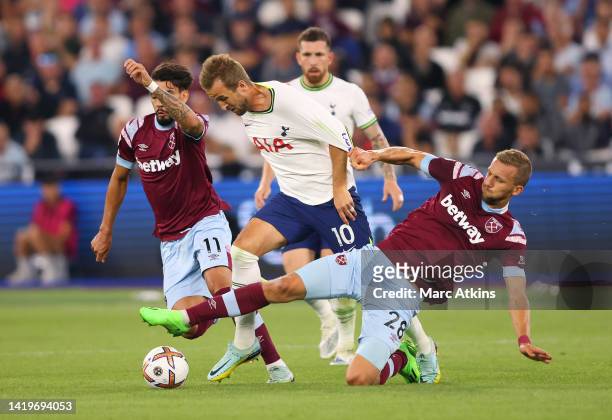 Harry Kane of Tottenham Hotspur is challenged by Lucas Paqueta and Tomas Soucek of West Ham United during the Premier League match between West Ham...