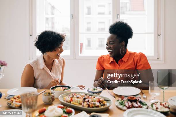 amigos felices y diversos sentados a la mesa y hablando entre sí - brunch fotografías e imágenes de stock