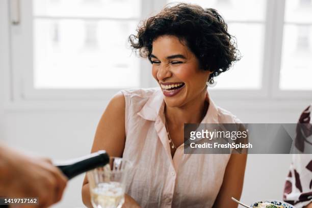 a beautiful woman laughing while being poured a glass of wine - rubbing alcohol stock pictures, royalty-free photos & images