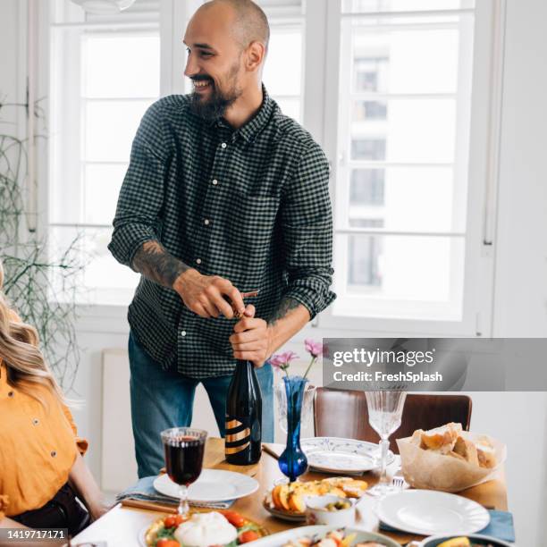 a happy handsome man opening a bottle of wine during lunch - wine white color stock pictures, royalty-free photos & images