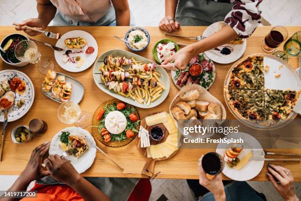 a from above view of a table full of delicious food eaten by unrecognizable multiethnic group of people - aantal mensen stockfoto's en -beelden