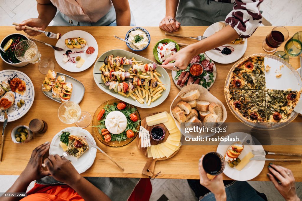 A From Above View Of A Table Full Of Delicious Food Eaten By Unrecognizable Multiethnic Group Of People