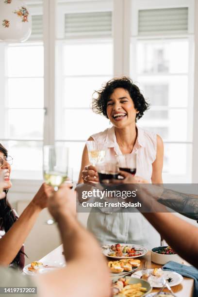 a beautiful happy woman standing and making a toast while being with her diverse friends - victory dinner stockfoto's en -beelden