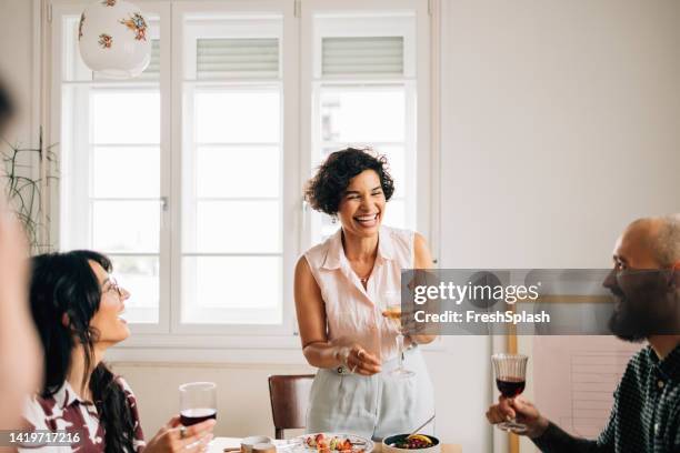 une belle femme heureuse debout et portant un toast tout en tenant une coupe de champagne - party host stock photos et images de collection