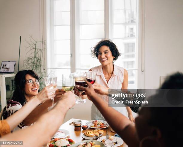 a beautiful happy woman standing and making a toast while being with her diverse friends - champagne brunch stock pictures, royalty-free photos & images