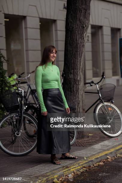 Aguest wearing apple green turtle neck top, long black leather skirt and sandals outside Rodebjer show in Stockholm fashion week Spring / Summer 2023...