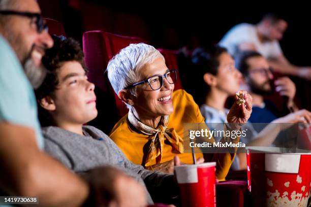 grandparents enjoying a movie with a little girl at the cinema - 50 watching video stock pictures, royalty-free photos & images