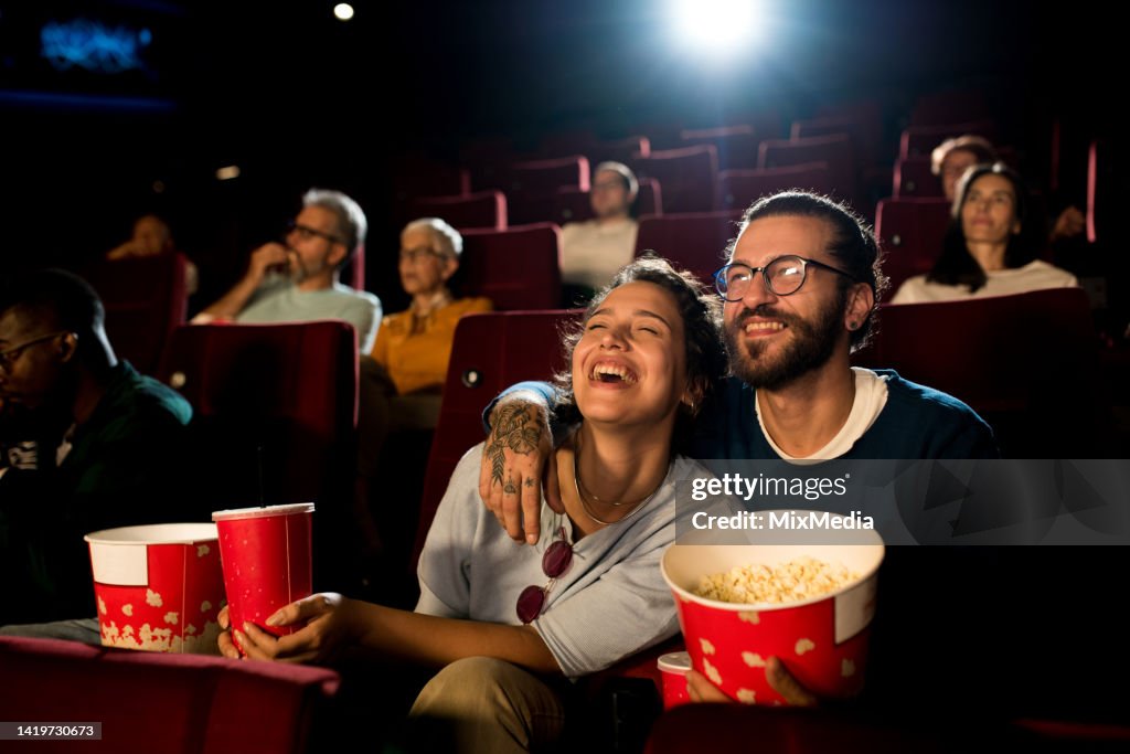 Young couple enjoying a fun movie at the cinema
