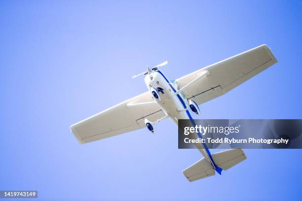 small plane flying overhead against blue sky - propellermaschine stock-fotos und bilder