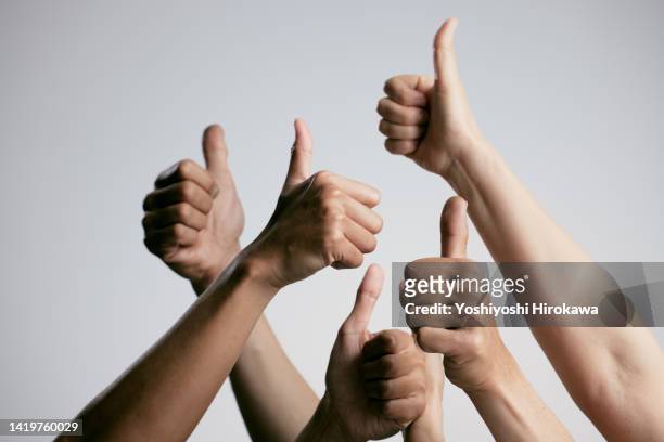 asians of other ethnic groups giving the thumbs up - vencer imagens e fotografias de stock