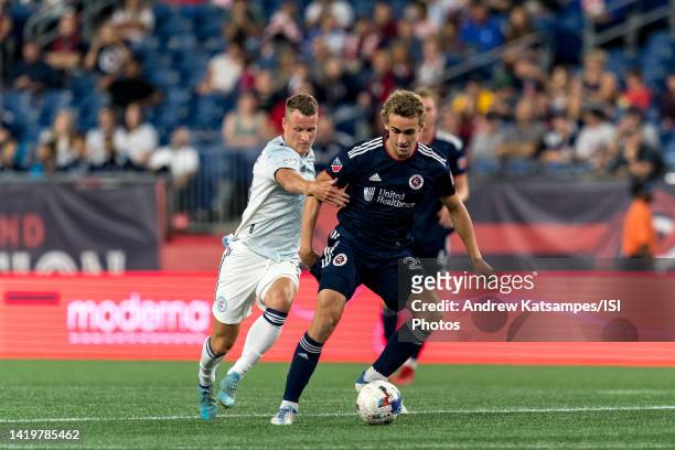 Noel Buck of New England Revolution dribbles as Chris Mueller of Chicago Fire FC defends during a game between Chicago Fire FC and New England...
