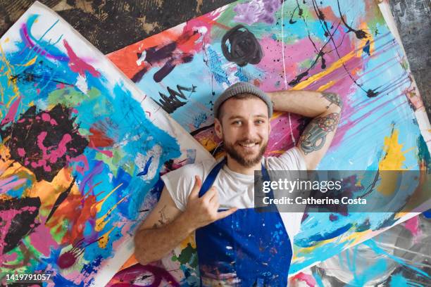 an aerial view of an artist laying on his abstract paintings - artist stock pictures, royalty-free photos & images