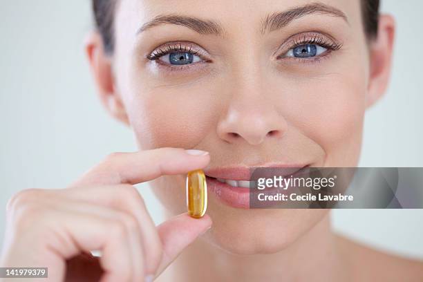 woman holding vitamined fish oil capsule - huile de foie de morue photos et images de collection