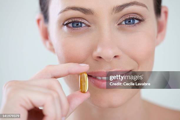 woman holding vitamined fish oil capsule - cod liver oil stock pictures, royalty-free photos & images