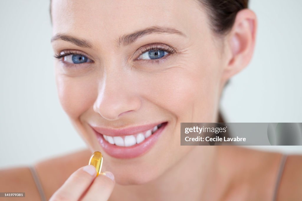 Woman taking vitamined fish oil capsule