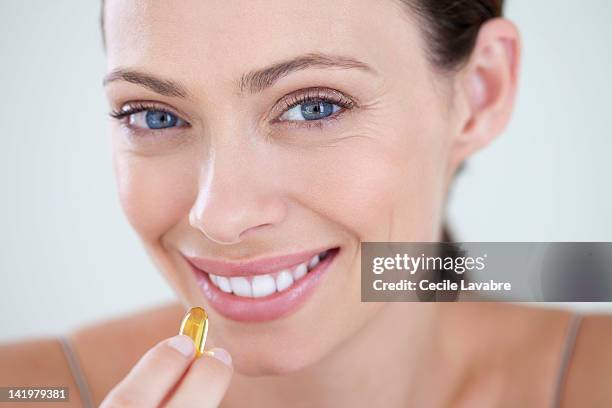 woman taking vitamined fish oil capsule - fish oil foto e immagini stock