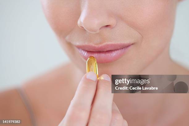 close up of a woman taking fish oil capsule - cod liver oil stock pictures, royalty-free photos & images