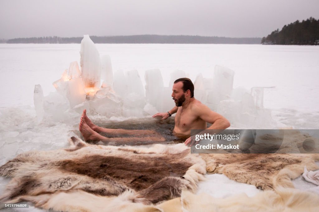 Mature man enjoying ice bath at frozen lake